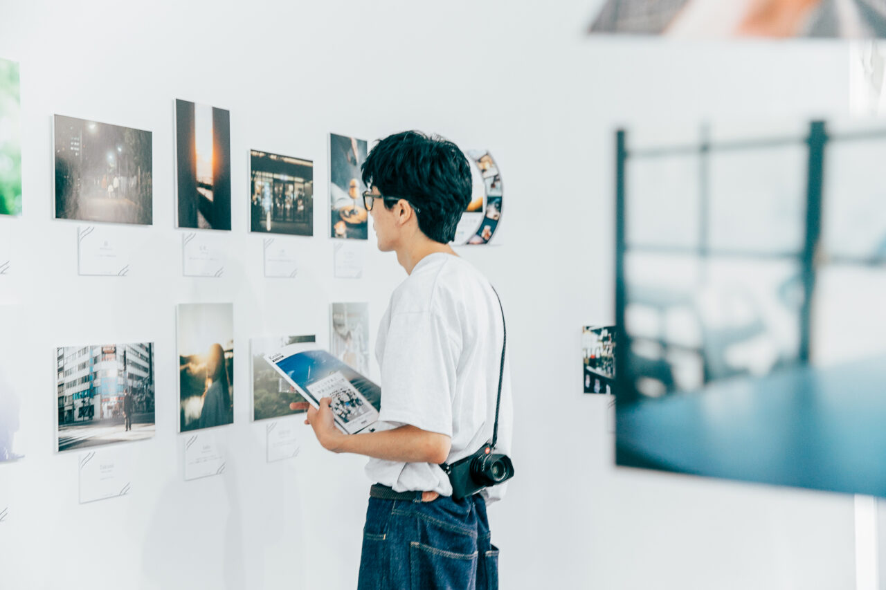 壁に並んだ写真作品を鑑賞する来場者